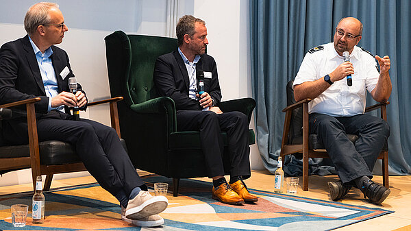 Foto von Christian von Spiczak-Brzezinski bei einer Podiumsdiskussion, neben Sebastian Klüsener und Thomas Wiatr.