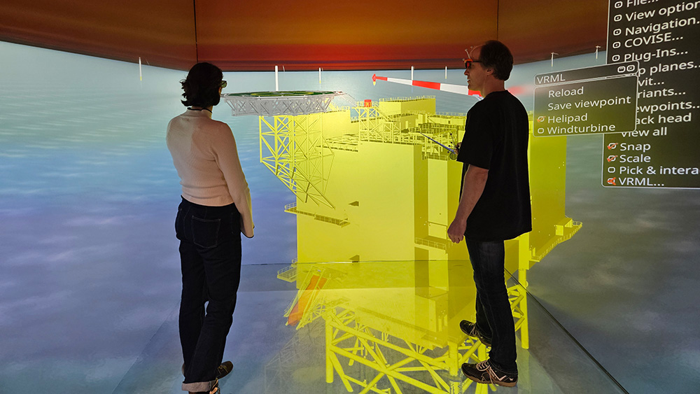 Two scientists discuss a 3D simulation of the structure at the based of a wind turbine.